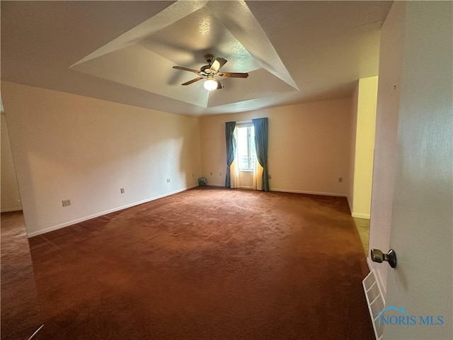 carpeted spare room with a tray ceiling and ceiling fan