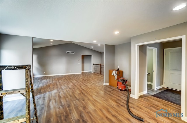 spare room with hardwood / wood-style flooring and vaulted ceiling