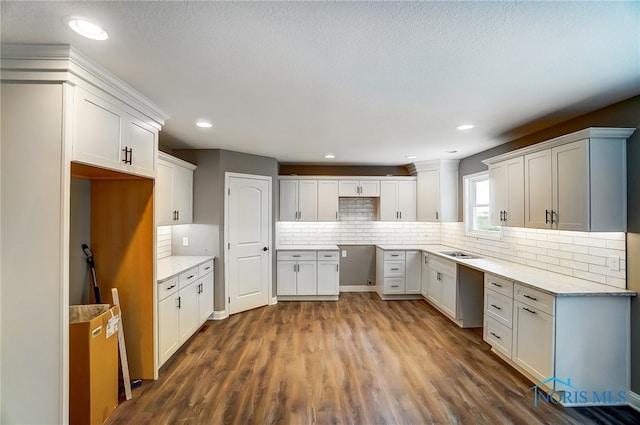 kitchen with backsplash, dark wood-type flooring, and white cabinetry