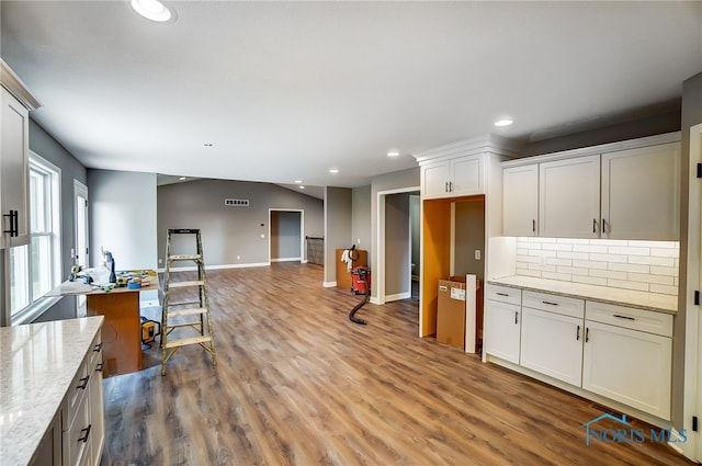 kitchen with white cabinetry, light stone countertops, tasteful backsplash, and hardwood / wood-style floors