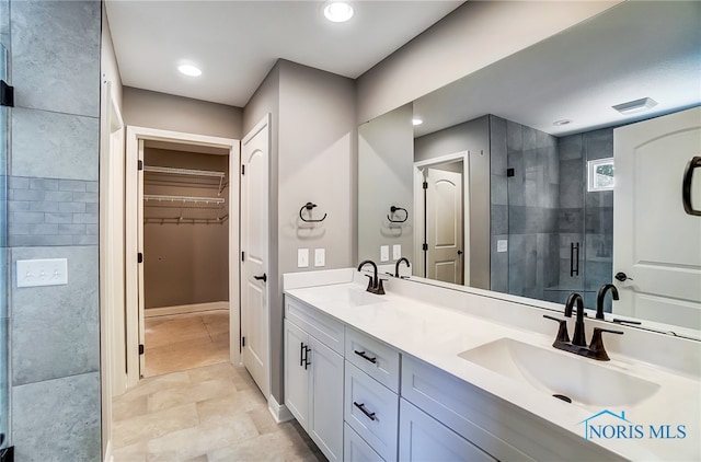 bathroom with a shower with door, tile flooring, and double sink vanity