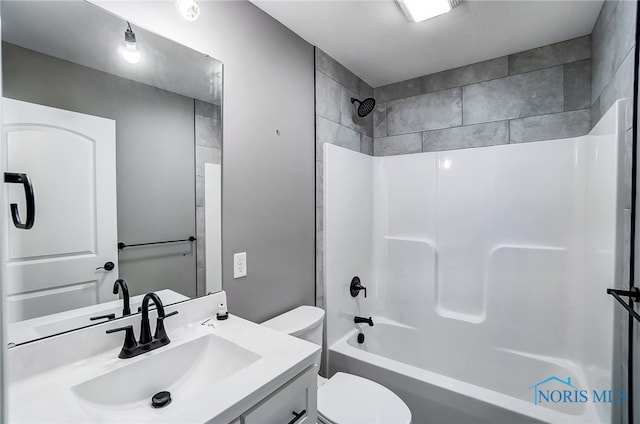 full bathroom featuring a textured ceiling, vanity, toilet, and tiled shower / bath combo