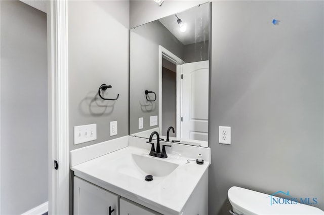 bathroom featuring vanity with extensive cabinet space and toilet