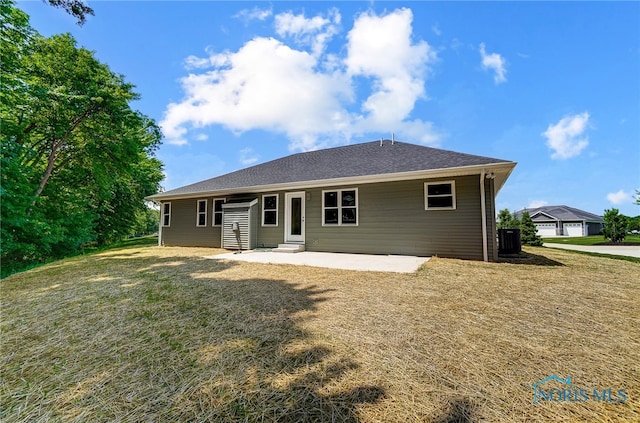 rear view of property with a garage, a patio area, and a yard