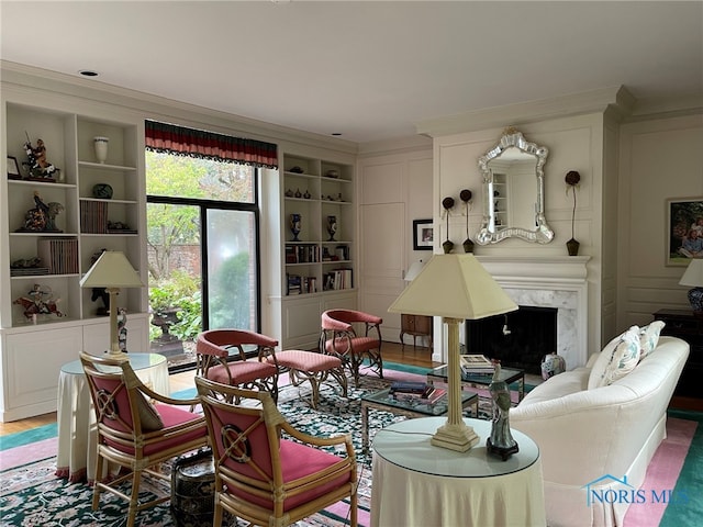 living room featuring built in shelves, ornamental molding, hardwood / wood-style flooring, and a premium fireplace