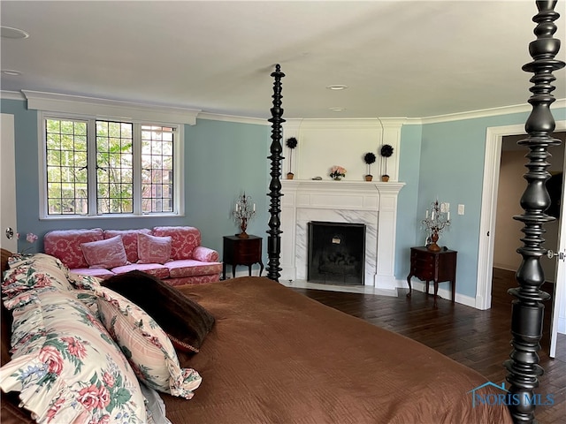 bedroom with ornamental molding, dark wood-type flooring, and a premium fireplace