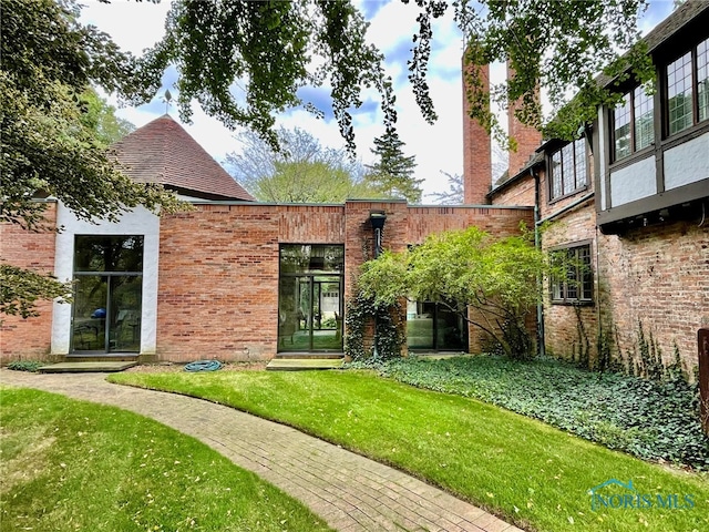 rear view of house with french doors and a lawn