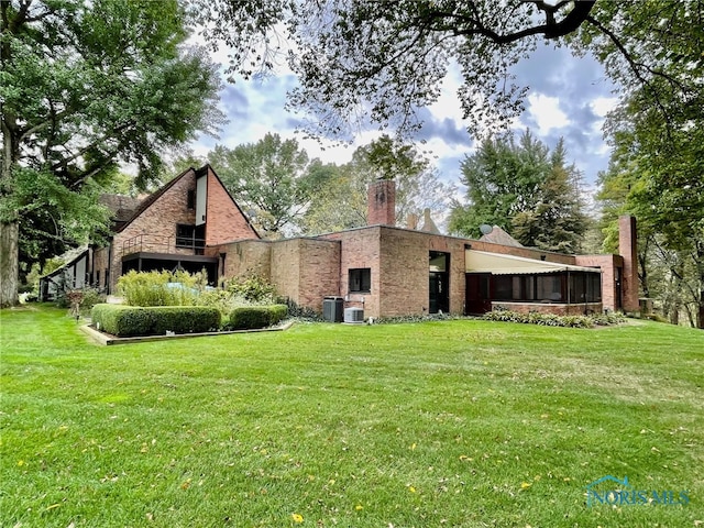 back of house featuring a yard and central AC