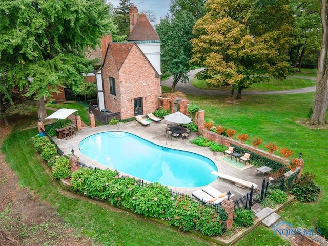 view of pool with a yard, a diving board, and a patio