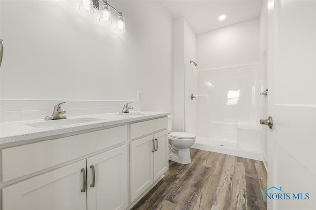 bathroom with vanity, toilet, hardwood / wood-style floors, and a shower