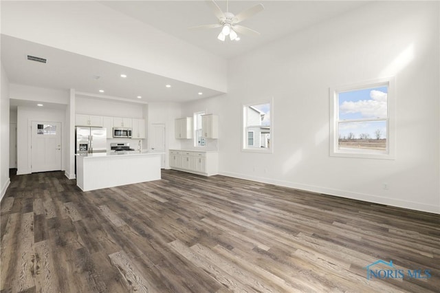 unfurnished living room featuring ceiling fan and dark hardwood / wood-style flooring