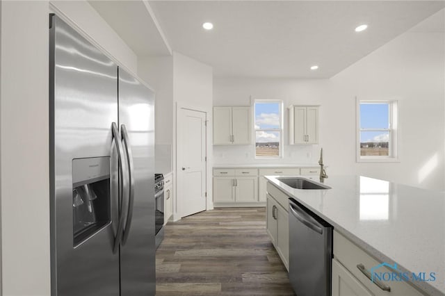 kitchen featuring stainless steel appliances, light stone countertops, sink, and white cabinets