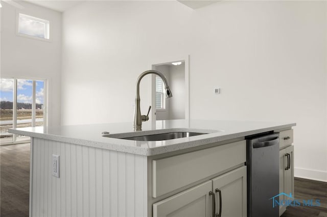 kitchen with sink, dark wood-type flooring, light stone countertops, and dishwasher