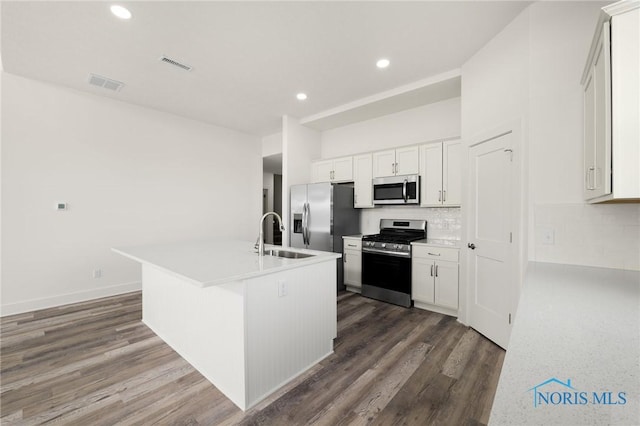 kitchen with sink, white cabinetry, stainless steel appliances, a kitchen island with sink, and decorative backsplash