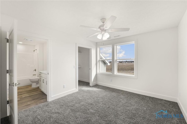 unfurnished bedroom featuring connected bathroom, carpet, a spacious closet, ceiling fan, and a closet