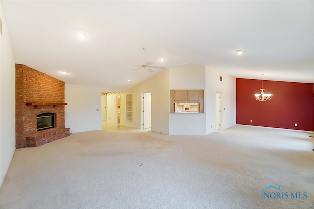 unfurnished living room featuring a fireplace, ceiling fan with notable chandelier, brick wall, light colored carpet, and high vaulted ceiling