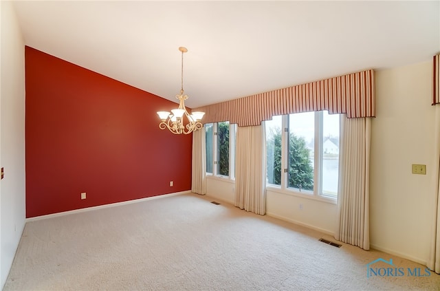 spare room featuring a notable chandelier and light colored carpet