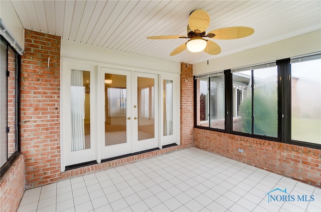 unfurnished sunroom featuring ceiling fan and french doors