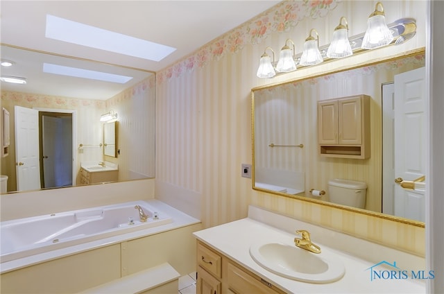 bathroom featuring a skylight, a bathing tub, tile floors, vanity with extensive cabinet space, and toilet