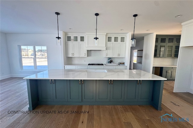 kitchen with light stone countertops, decorative backsplash, decorative light fixtures, and white cabinetry