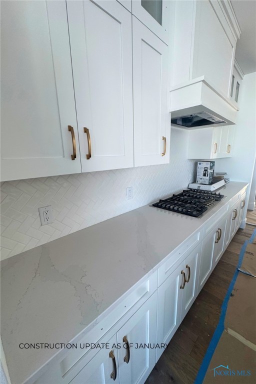 kitchen featuring white cabinetry, tasteful backsplash, light stone counters, dark hardwood / wood-style floors, and custom exhaust hood