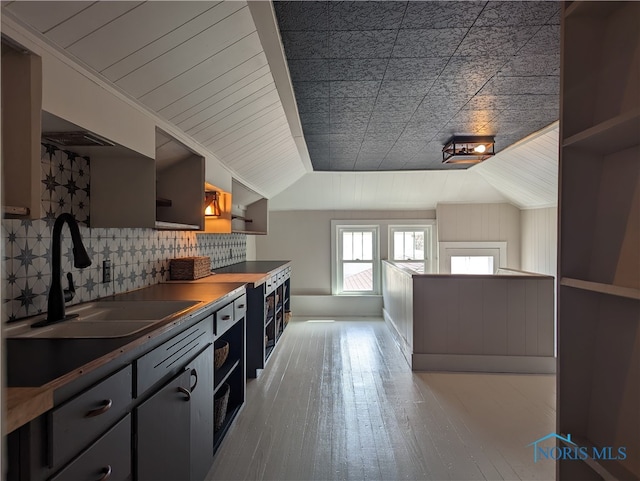 kitchen featuring sink, wood-type flooring, tasteful backsplash, and lofted ceiling