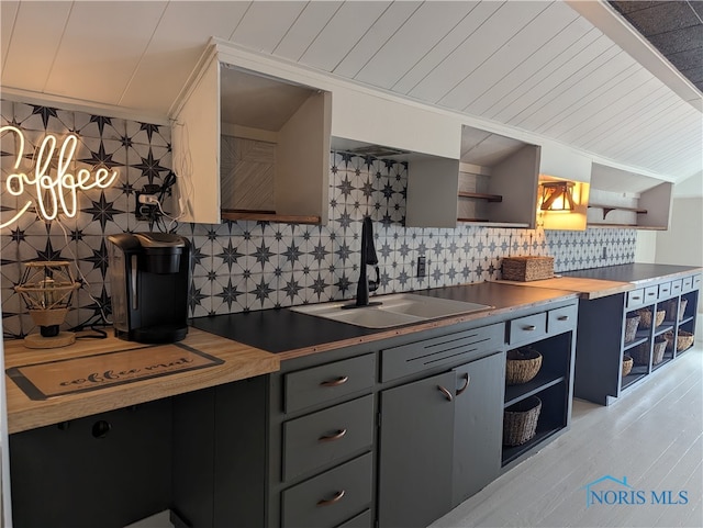 kitchen with decorative backsplash, gray cabinets, butcher block countertops, and sink