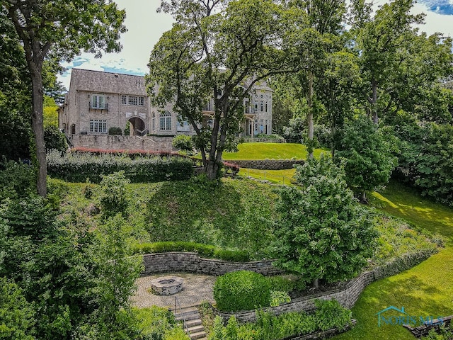 surrounding community with a fire pit and a lawn