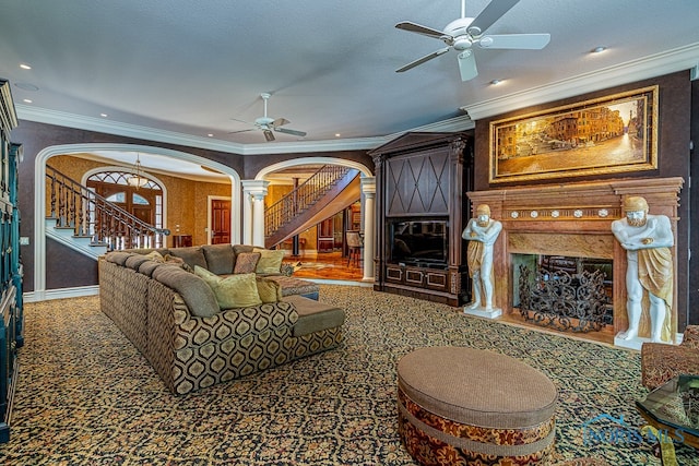 living room with a textured ceiling, ceiling fan, crown molding, and decorative columns