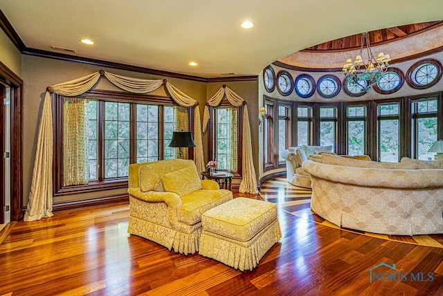 living area featuring ornamental molding, hardwood / wood-style floors, and an inviting chandelier