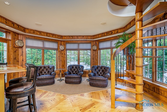 living room with light parquet flooring, a wealth of natural light, and wood walls