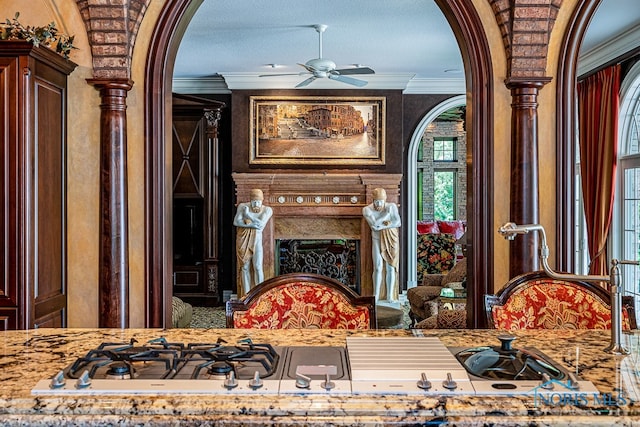 living area featuring ornamental molding, ceiling fan, and decorative columns