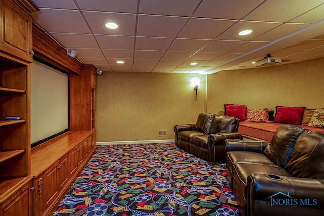 carpeted home theater room with a drop ceiling