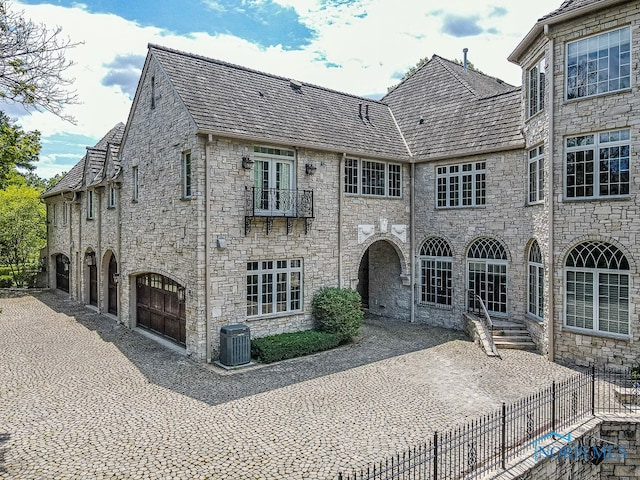 back of property featuring central AC unit, a garage, and a patio area