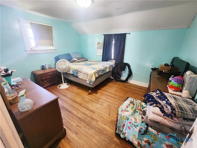 bedroom with vaulted ceiling and light wood-type flooring