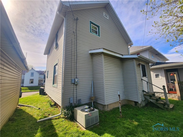 exterior space with central AC unit and a lawn