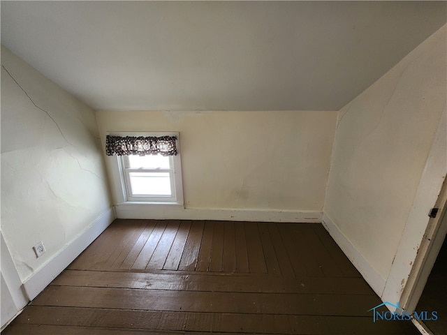 unfurnished room featuring dark wood-type flooring and lofted ceiling