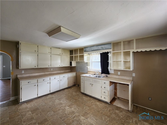 kitchen with sink, white cabinetry, and dark tile floors