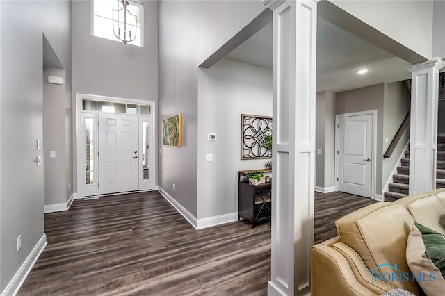 entrance foyer featuring ornate columns, dark hardwood / wood-style flooring, and a towering ceiling