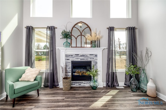 sitting room with hardwood / wood-style flooring, a towering ceiling, and a fireplace