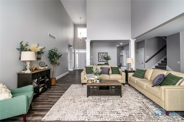 living room featuring ornate columns, dark wood-type flooring, and a high ceiling