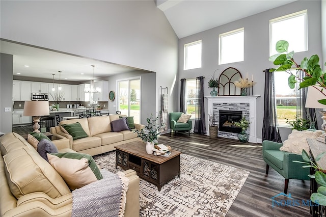 living room with a tiled fireplace, plenty of natural light, hardwood / wood-style floors, and a notable chandelier