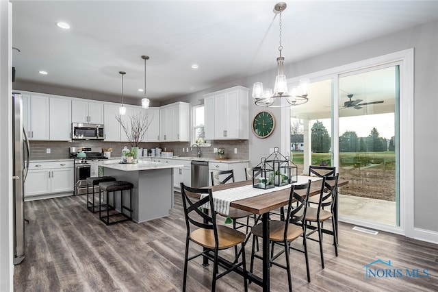 dining area featuring ceiling fan with notable chandelier, dark hardwood / wood-style floors, and sink