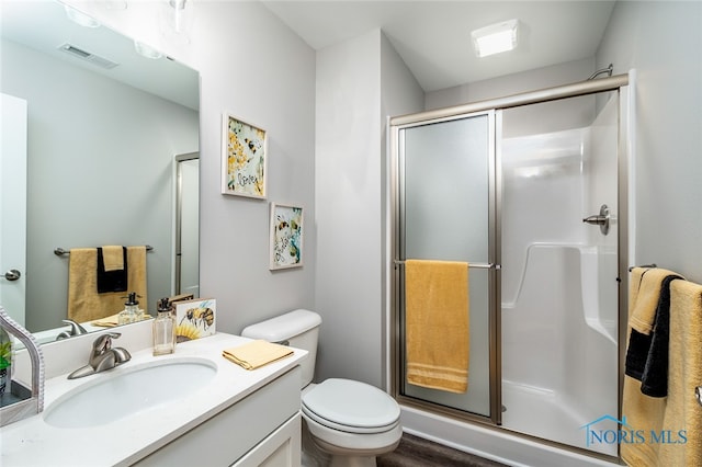 bathroom with hardwood / wood-style floors, vanity, an enclosed shower, and toilet