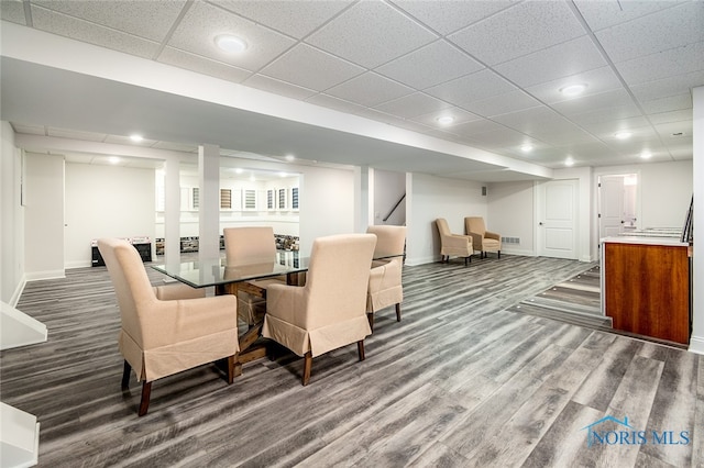 dining space featuring a drop ceiling and dark wood-type flooring