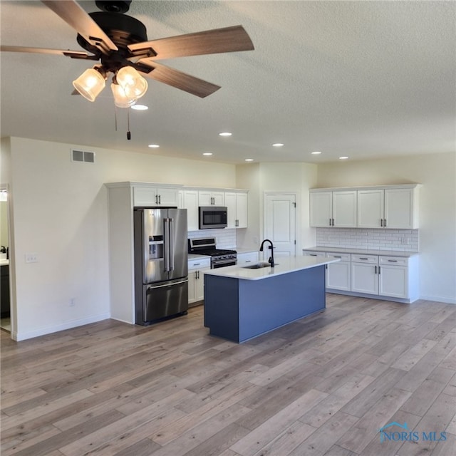 kitchen featuring decorative backsplash, white cabinets, light hardwood / wood-style flooring, and stainless steel appliances