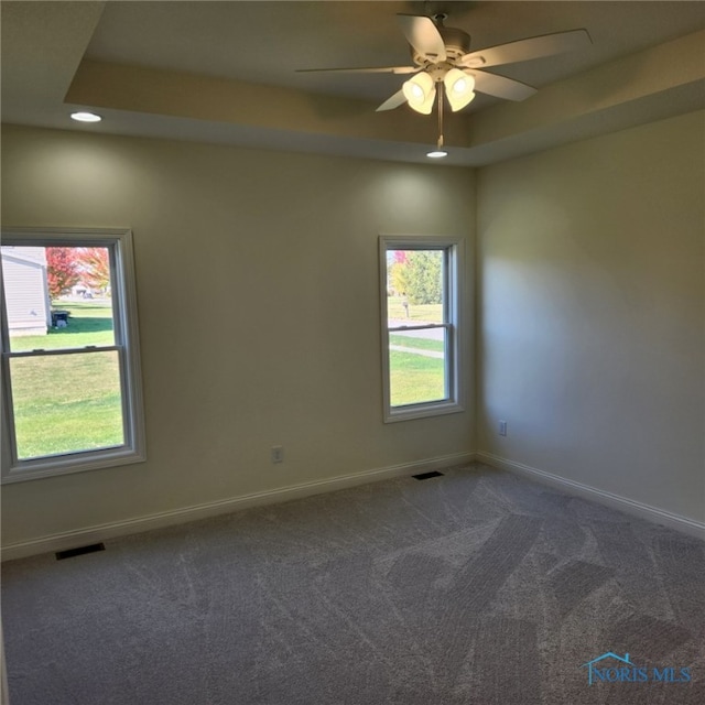 carpeted empty room with ceiling fan and a raised ceiling