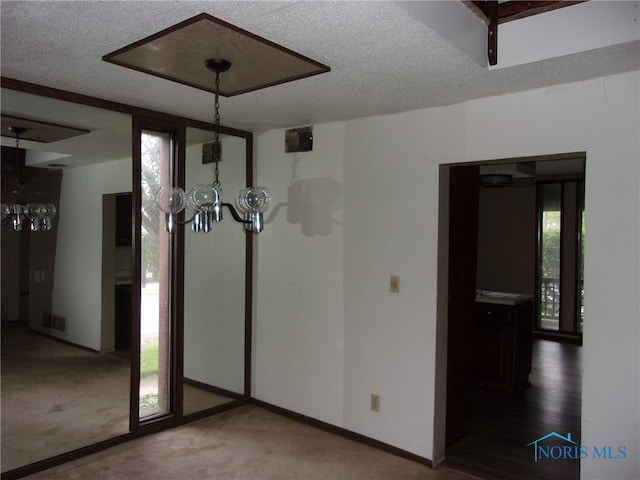 unfurnished dining area featuring carpet flooring, an inviting chandelier, and a textured ceiling