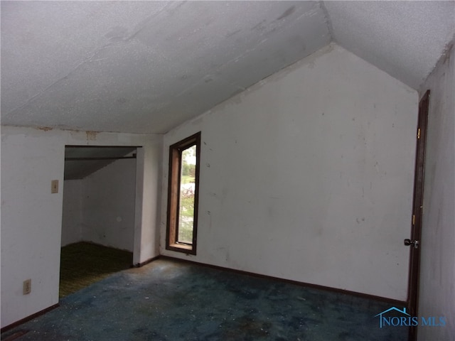 carpeted empty room featuring lofted ceiling and a textured ceiling