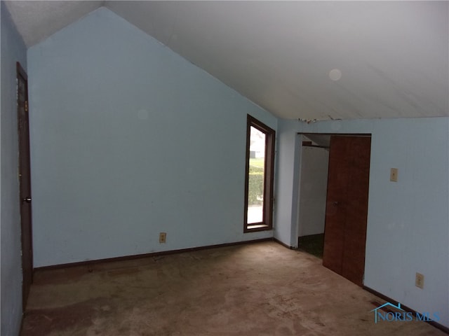 carpeted spare room with vaulted ceiling